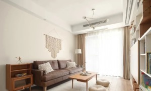 木地板加铺米白色棉织地毯，材质与沙发背景的墙饰以及靠枕相呼应，沙发也极具造型，给人眼前一亮的感觉