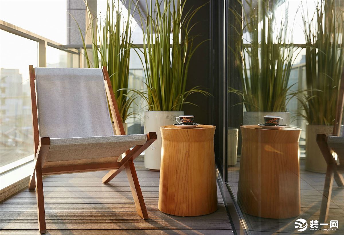 客厅外的阳台，以玻璃隔断，一张凳子，一个茶几，以原木为主的材质，在阳光的照射下，散发温暖。