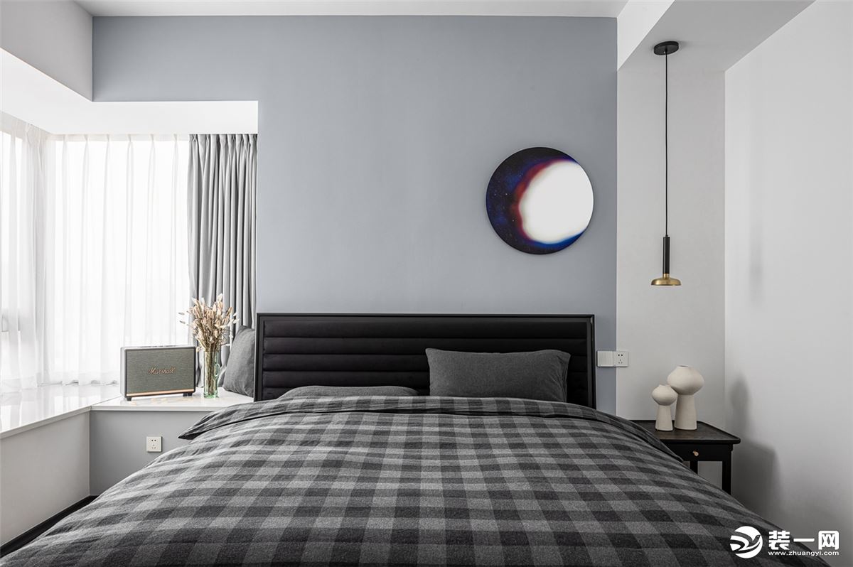 卧室床头墙蓝白渲染的挂饰，深灰色的背景墙，与拐角的飘窗设计，布置简约自然的床单，显得静雅温馨而舒适。
