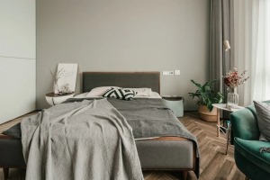 卧室全貌2——采光极好的落地窗前是一张轻奢欧风的深绿色沙发榻，和卧室内的其他绿植一起点缀着灰、白、木