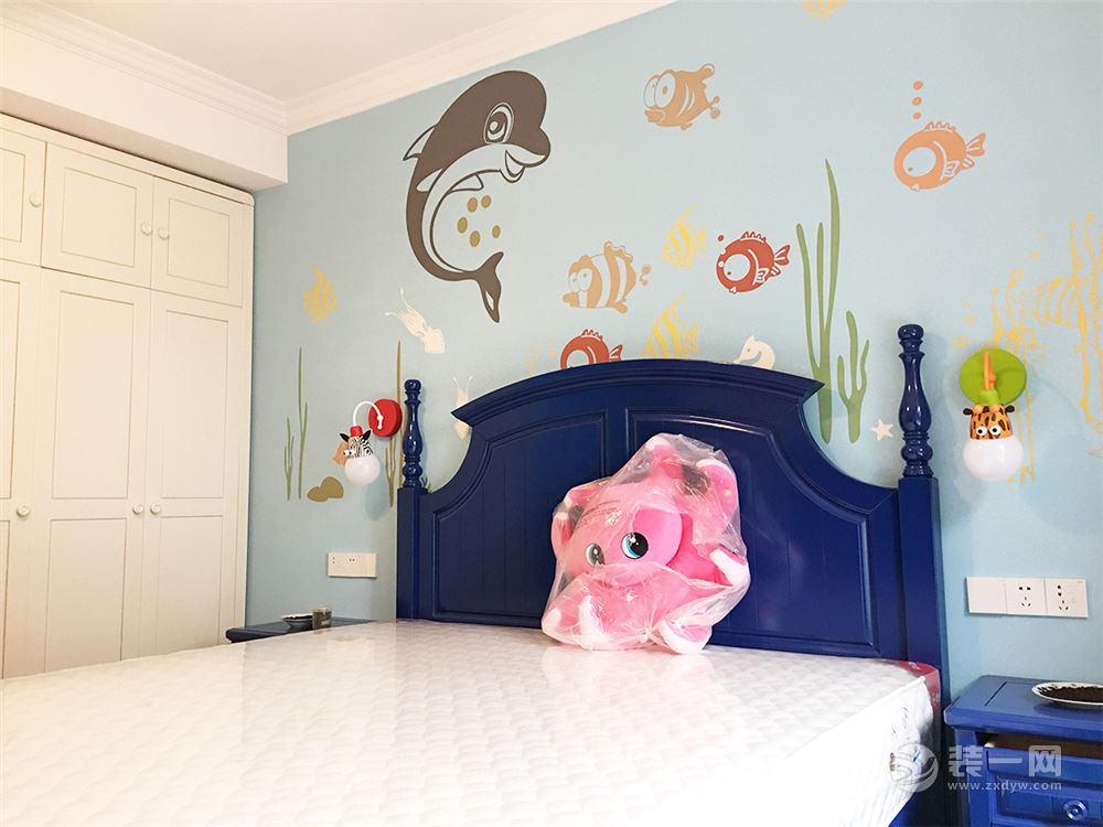 主卧将地中海风格惯用的蓝色和白色的作为整个主卧室的色调，背景墙则是用灰蓝色油漆涂刷，小海豚和小鱼群使