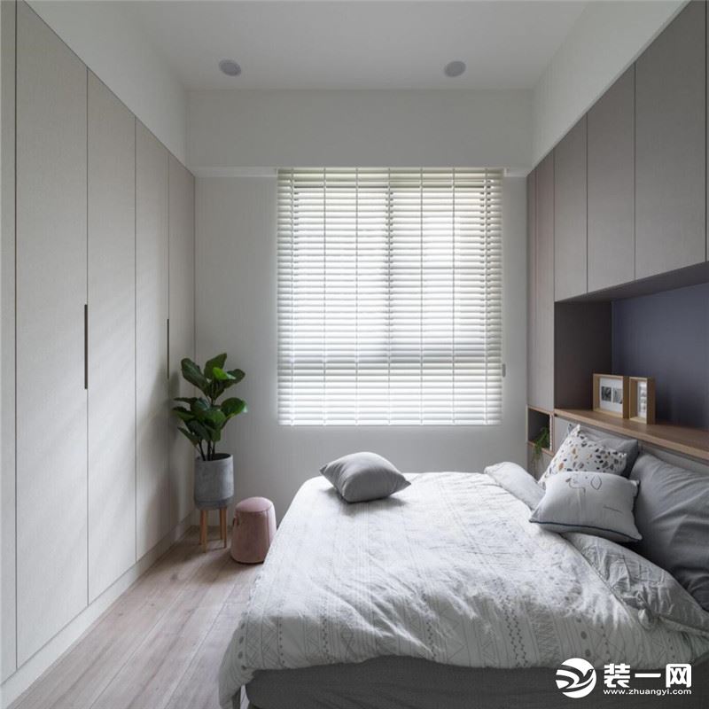 为了增加主卧室的储物空间，设计师结合床头柜增加衣柜，并延续着木质元素，使空间形成统一