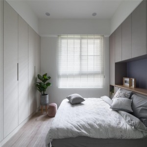为了增加主卧室的储物空间，设计师结合床头柜增加衣柜，并延续着木质元素，使空间形成统一
