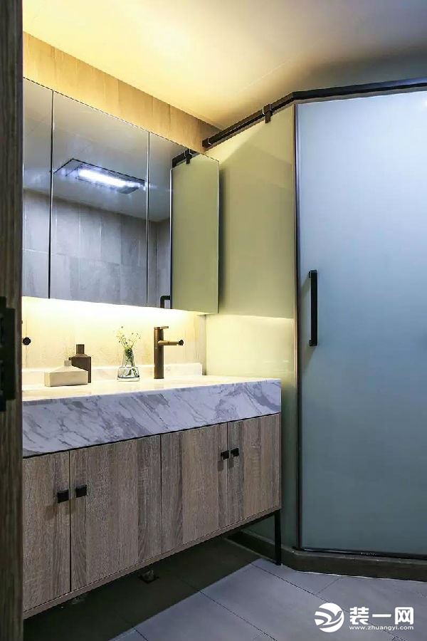 卫生间内部是三角形的布局方案，钻石形的淋浴房做在了转角处，两侧摆放洗手台和马桶。洗手台上方的镜柜做了