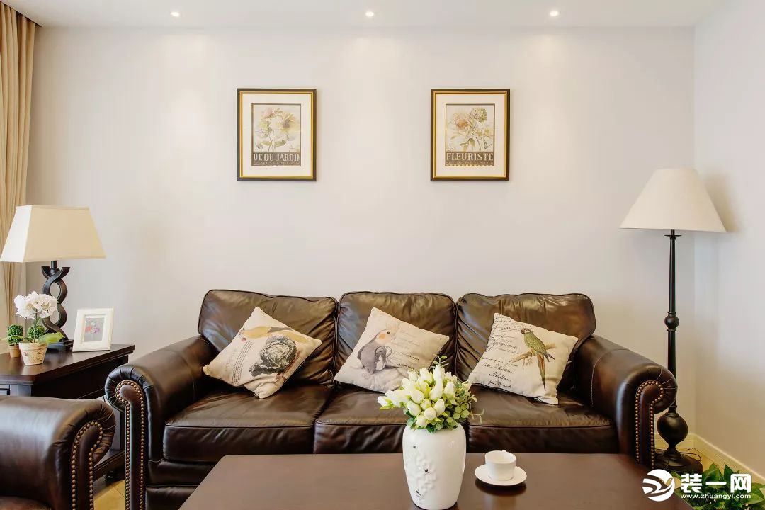 浅灰色墙面搭配深色美式家具，客厅中的主灯采用复古鎏金灯体手工锻造的铜灯。