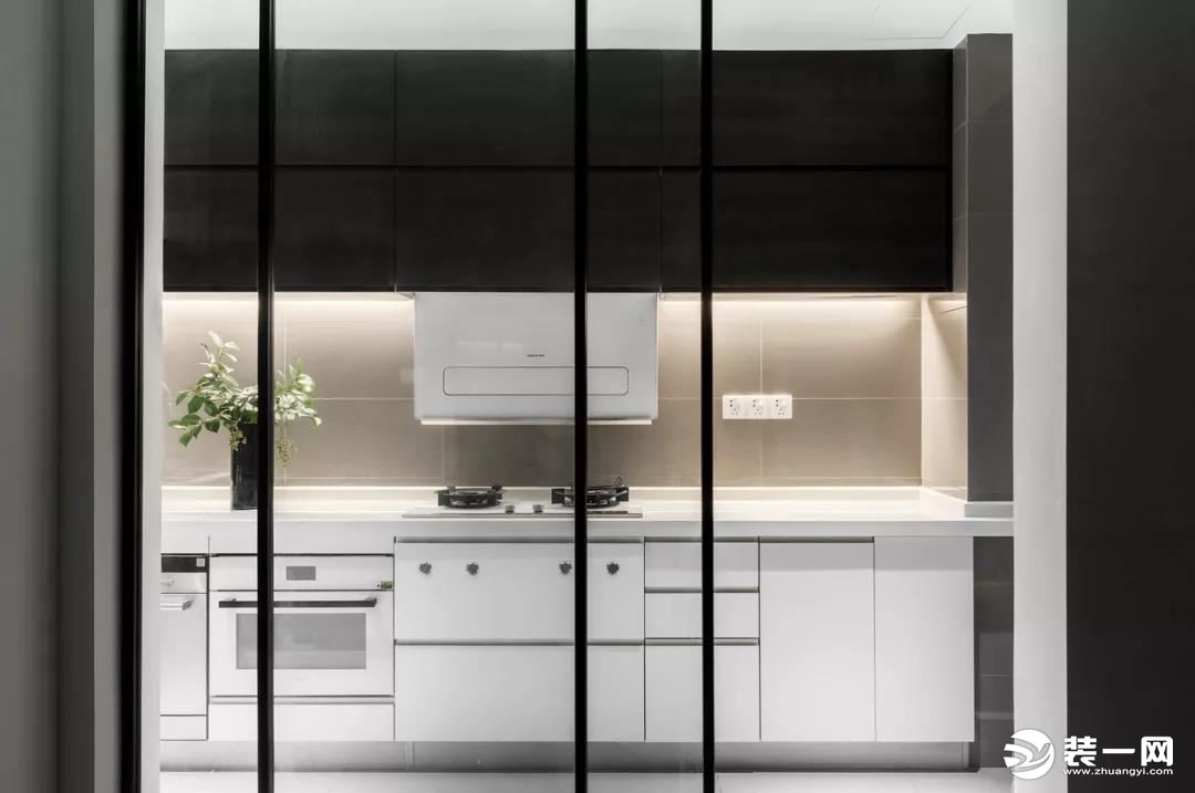 厨房设计了白色的橱柜+黑色的吊柜，吊柜做了藏光的设计，在强烈的色彩对比下更凸显层次感