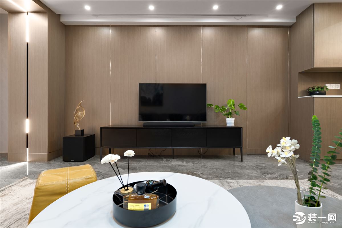 电视背景墙选用木饰面，有序嵌入金属线条，凸显轻奢质感，也延伸了空间感。其中右侧设置了一道隐形门