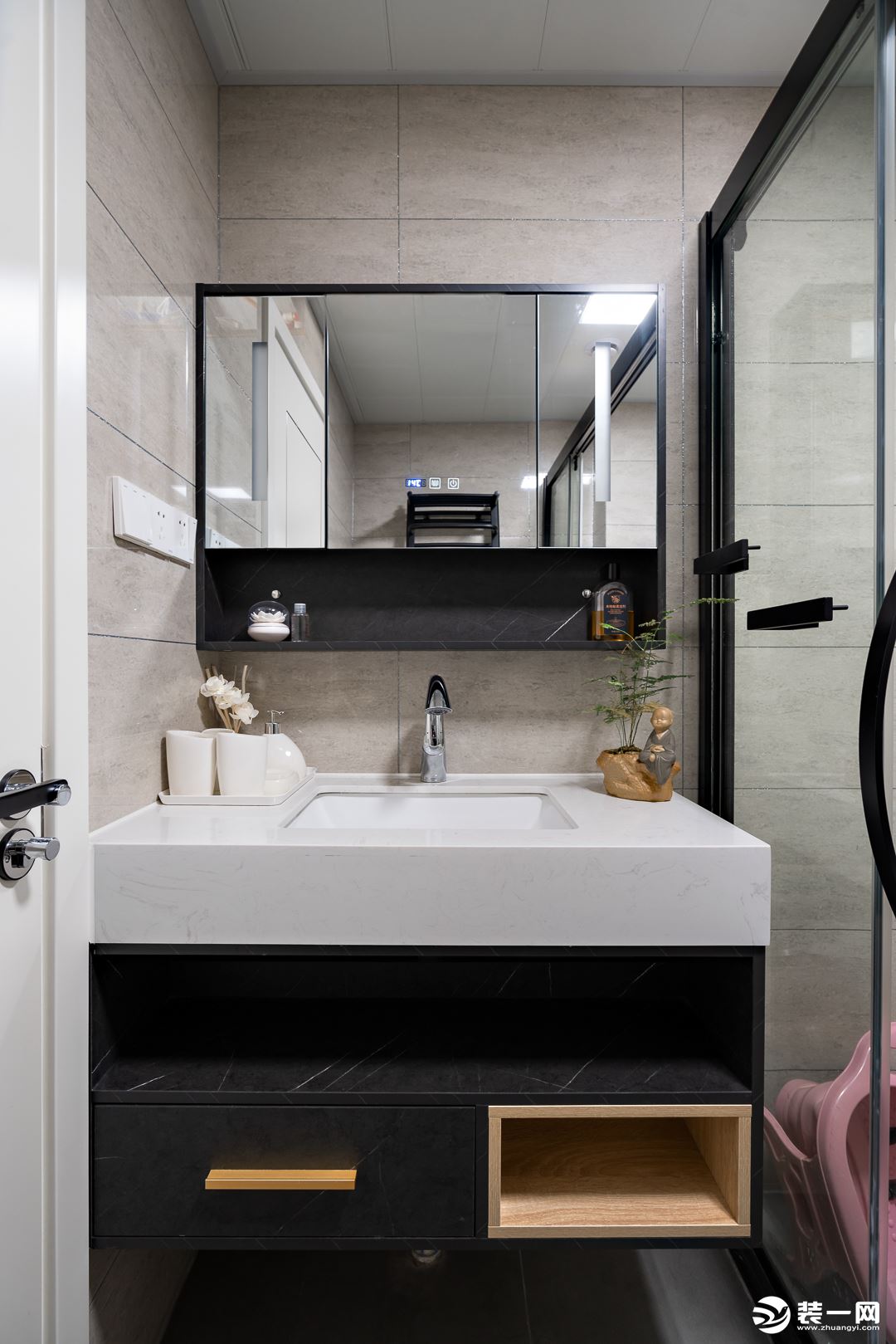  卫浴空间以黑白灰为主调，突显了空间的简洁大气，盥洗镜与玻璃淋浴房均以黑色金属线条包边，视觉上更加整