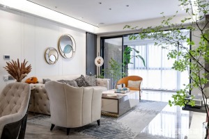 客厅的设计是非常通透、干净的，有弧度造型的沙发、座椅以及背景墙面的圆形金属挂件，让整体看起来非常圆润