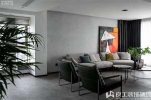 客厅整体是素雅大方的黑白灰。灰色墙布拼贴的墙面搭配一幅橙色点缀的跳跃性挂画，以艺术化的视觉呈现