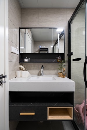  卫浴空间以黑白灰为主调，突显了空间的简洁大气，盥洗镜与玻璃淋浴房均以黑色金属线条包边，视觉上更加整