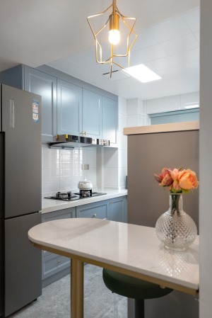 厨房空间采用开放式形式，浅蓝色柜体搭配白色瓷砖，