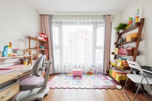 儿童房暂未设床，而是打造成了宝宝的阅读玩耍区。每个阶梯式置物架上有序放满了童书和玩具。