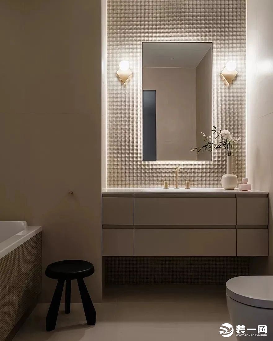 浴室选用米白色作为空间的主色调，搭配上偏暖的灯光，营造出了一个温馨的空间氛围。洗手台上的植物增添美感