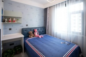 儿童房的墙面贴着海洋主题的船形图案墙布，布置一张蓝色皮艺床+床单，摆上玩偶充满童真