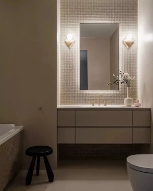 浴室选用米白色作为空间的主色调，搭配上偏暖的灯光，营造出了一个温馨的空间氛围。洗手台上的植物增添美感