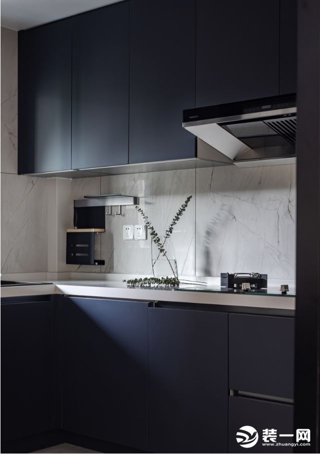 厨房定制了L型的橱柜，另一侧摆放冰箱，黑色橱柜与浅灰瓷砖的搭配，在光线的晕染下营造出一份静谧与雅致。