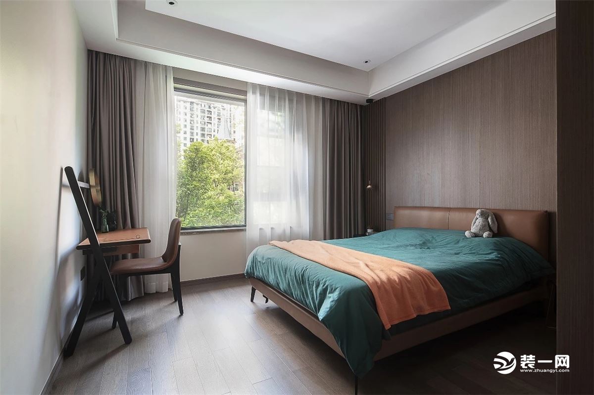次卧的色调延续整个空间的特色，在风格上保持一致，透过窗帘映入室内的光线与鲜活橙色布艺让睡眠区更为柔软舒适。