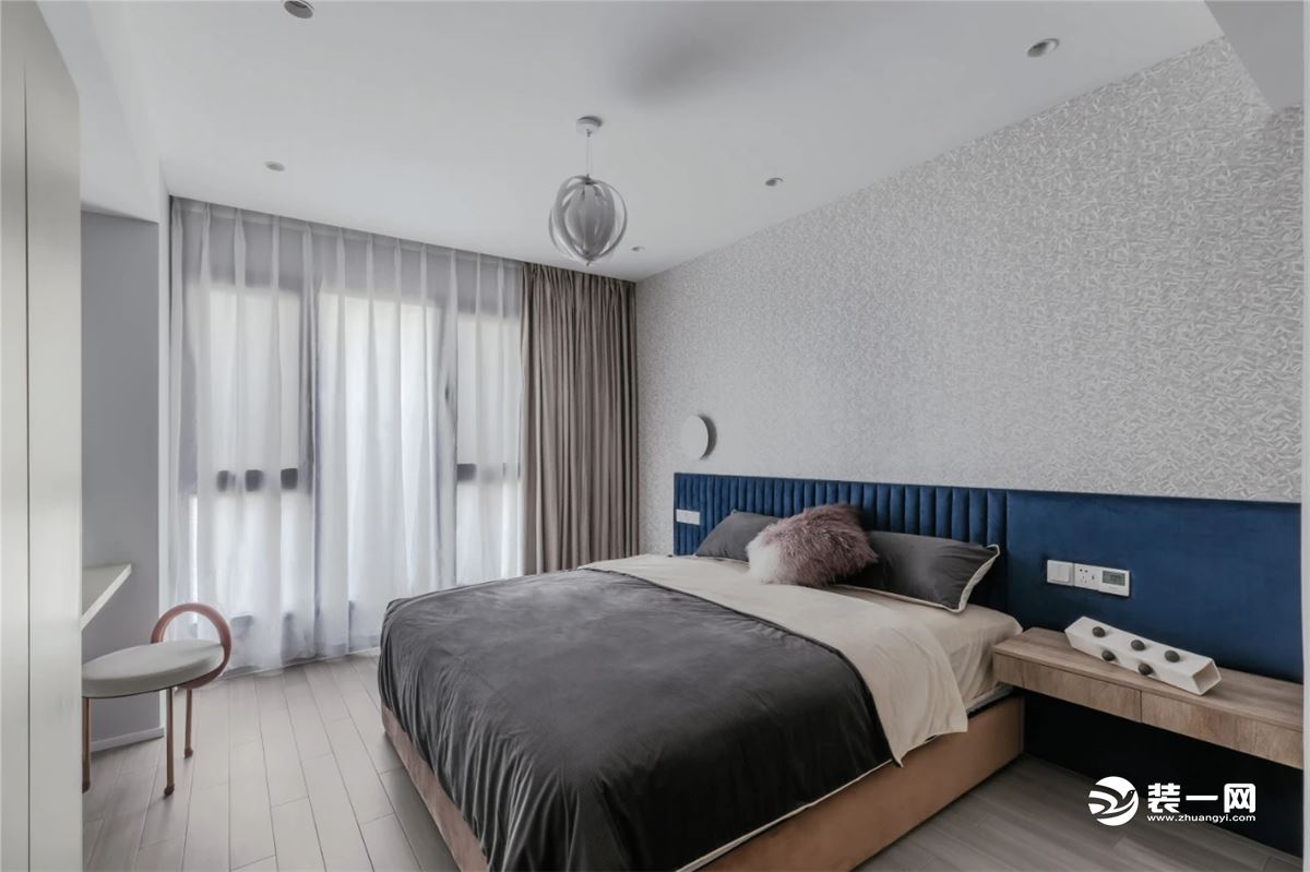床头墙是定制的悬空款式设计，床头墙贴着灰色独特的墙布，床铺搭配灰色床单，整体简约舒适而自然。