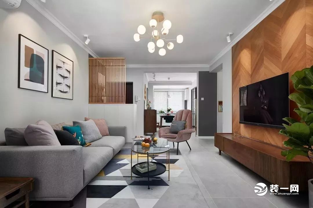 客厅的电视背景墙用鱼骨拼的木地板组成，浅灰色的布艺沙发搭配灰色哑光砖，整个客厅给人一种轻松、舒适感。
