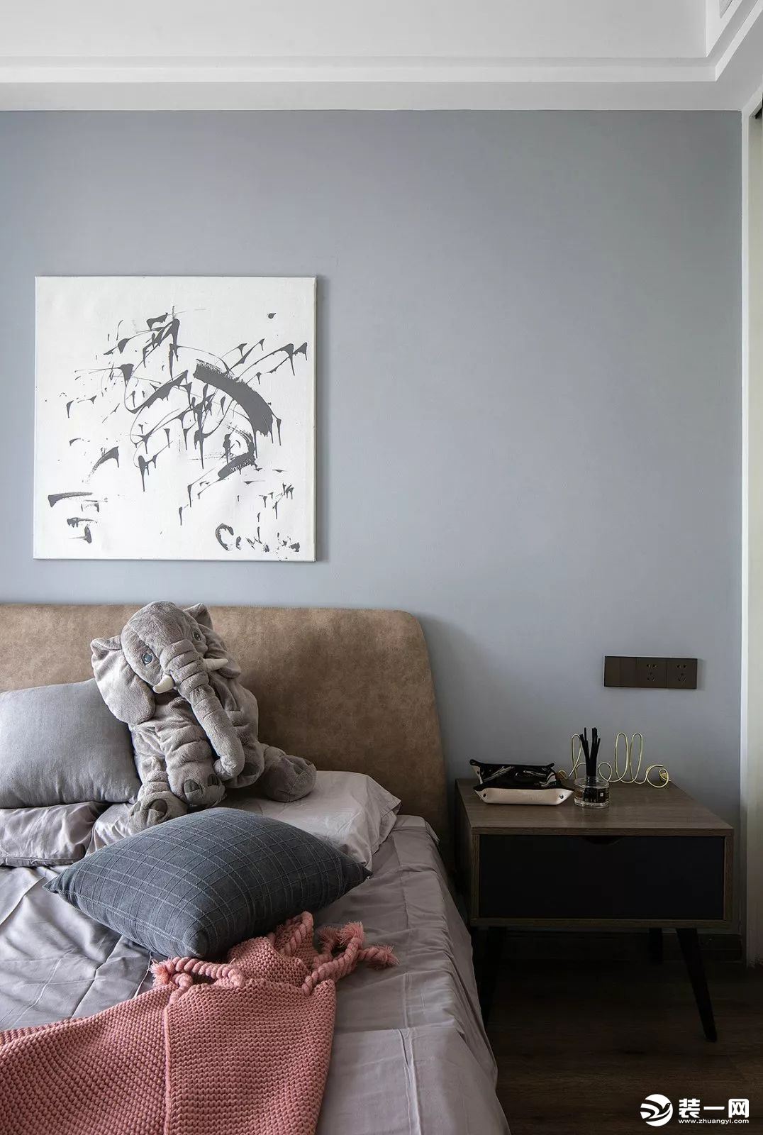 次卧的床头背景墙刷成了蓝灰色，搭配随意极简的装饰画、棕灰色的床头靠背，营造一个轻松松的空间。