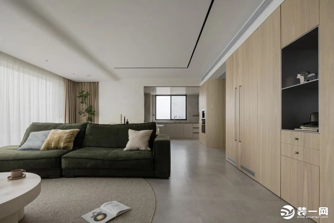 白色的顶面哑灰的地面淡化视野的限定，木纹的柜体、墨绿色的沙发以及各个素雅的摆件使空间盎然灵动。