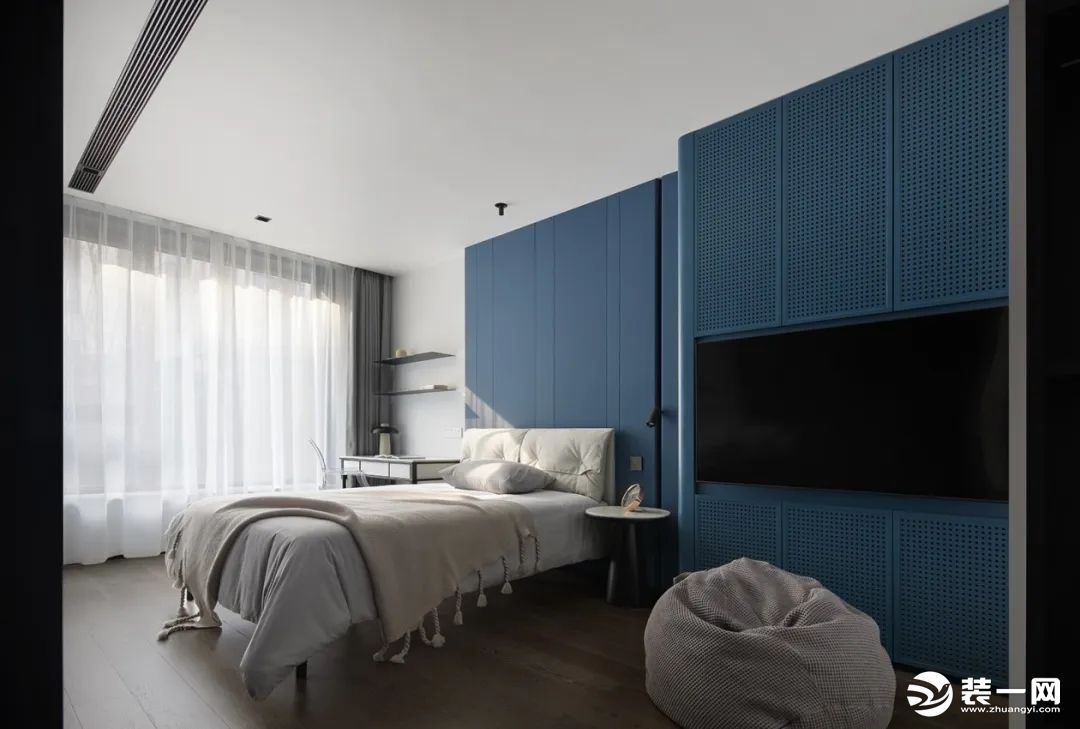 房间以轻柔稳重的深蓝色作为主色调；一整面墙的茶色玻璃收纳柜，是心爱手办的归宿。