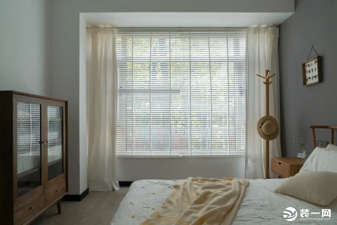 卧室柜子、衣架等木质元素自然且舒适，百叶窗与棉布窗帘结合，窗外景色虚虚实实。