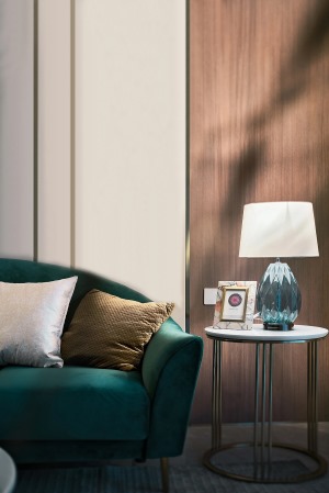 沙发背景以木饰面与硬包的拼叠组合形成精致的层次感，时髦与复古并存的墨绿色沙发静处于空间中央。