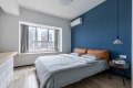 主卧，床头背景墙涂刷了蓝色的墙漆，加上了橙黄色的软包靠背，静谧且舒适却又带有一丝丝的活泼感。