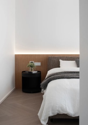 黑色的床头柜与电视的颜色相呼应，绿色盆栽的点缀将自然气息蔓延整个卧室内。