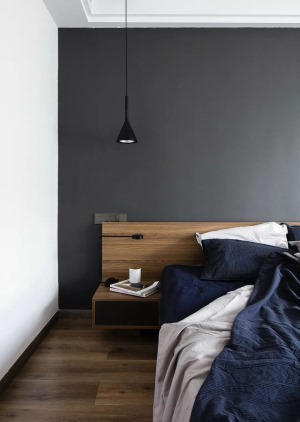 主卧室的床头背景墙刷成了深灰色，结合白色的墙面、吊顶和深蓝色的床品，给人一种精致大方的感觉。
