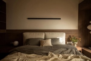 床头背景特意保持素净，“一字”壁灯既是装饰也为夜晚带来微亮的放松氛围，做了挑空处理，让空间隔而不断。