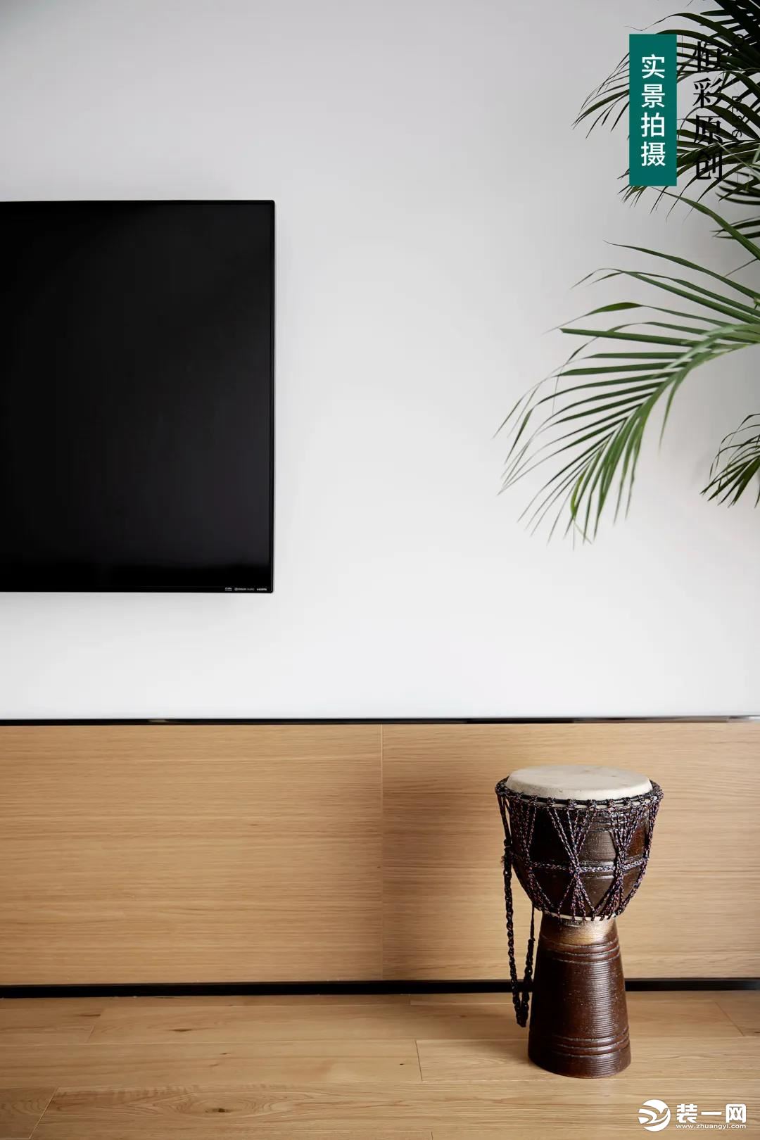 电视机背景墙利用木饰面和大白墙拼接，在整个木饰面背景下“框”出一片大白墙作为电视机背景。由地面到墙面