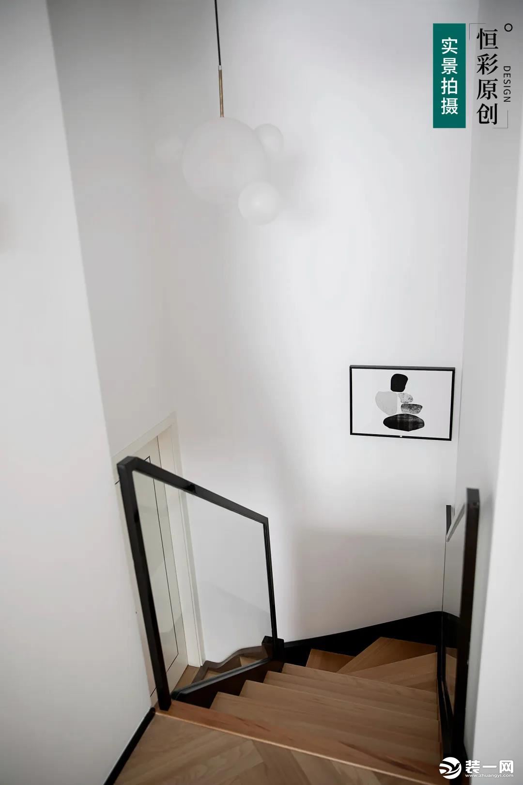  原木楼梯踏步板，搭配透明玻璃扶手，看上去更加通透、清爽。  白色吊灯在大白墙的衬托下存在感很低，不