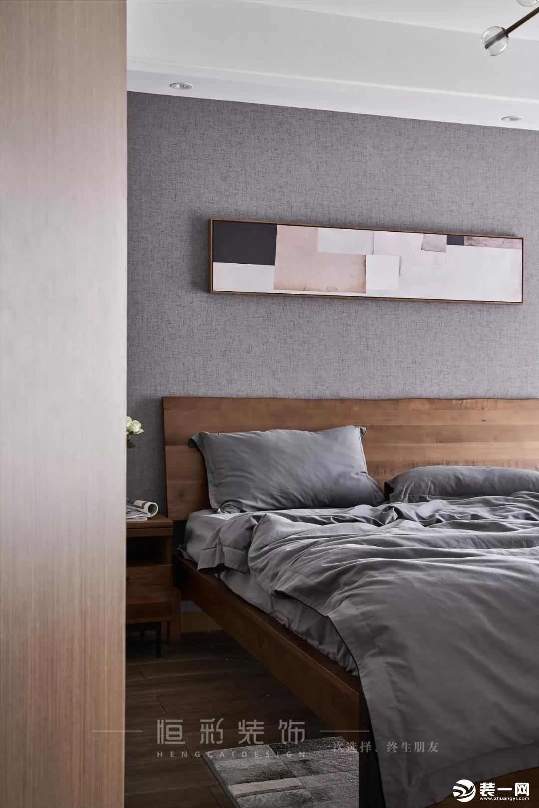 卧室空间整体配色呈浅灰色系。浅灰色墙纸搭配浅灰色的纯色床品，一种简单到极致的高级感便油然而生。木饰面