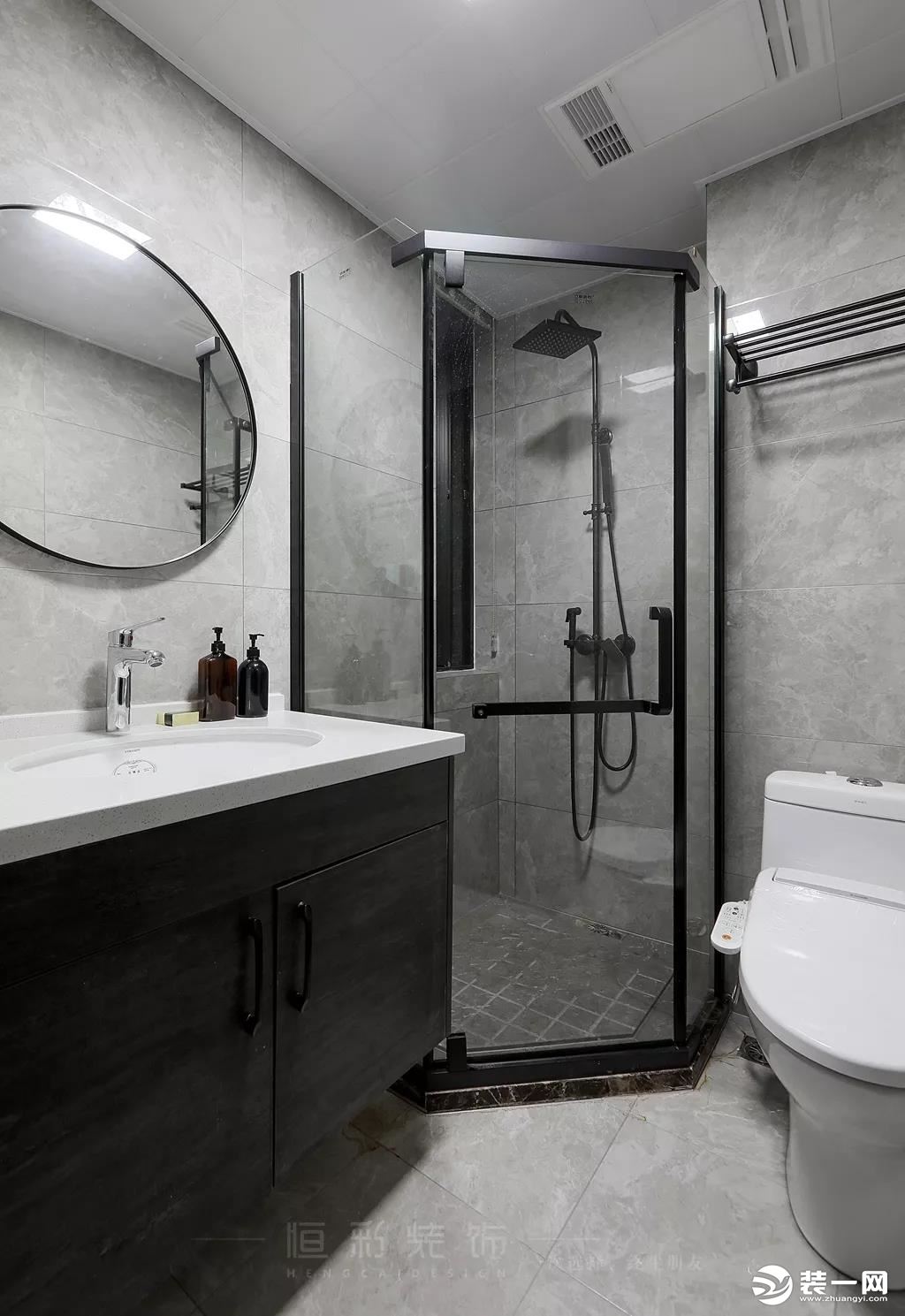 卫生间整体选用黑白灰色系配色，黑色淋浴房门框搭配黑色台盆柜，黑色边框圆镜点缀让空间设计感更足。搭配浅