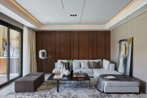 客厅以胡桃木为背景，搭配上灰色布艺沙发与地毯，地面布置小茶几，让客厅显得简约实用而舒适。      