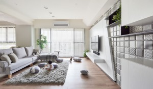简单的灰色沙发现代气息十足，搭配上木质的地板，一种温暖舒适的氛围在房间中蔓延开来。地毯柔软的纹理，很