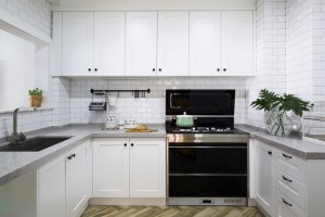 清新的整体氛围也同样延伸到了厨房， 橱柜与台面的大片纯白设计显得干净整洁，白色方格砖让空间增添现代感