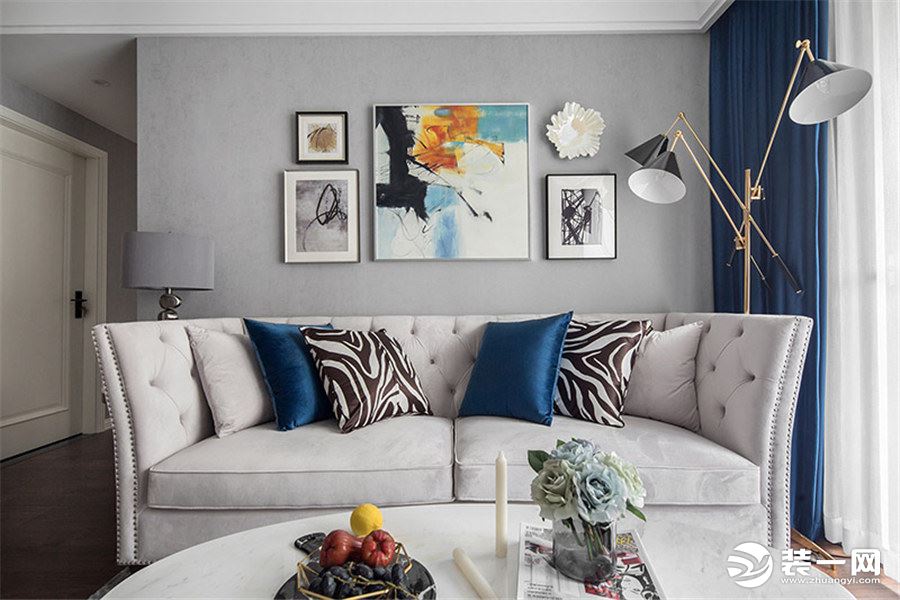 客厅的主要色调为灰蓝色，灰色的地毯，灰色的墙面，米白色的美式布艺沙发，充满活力，积极向上。