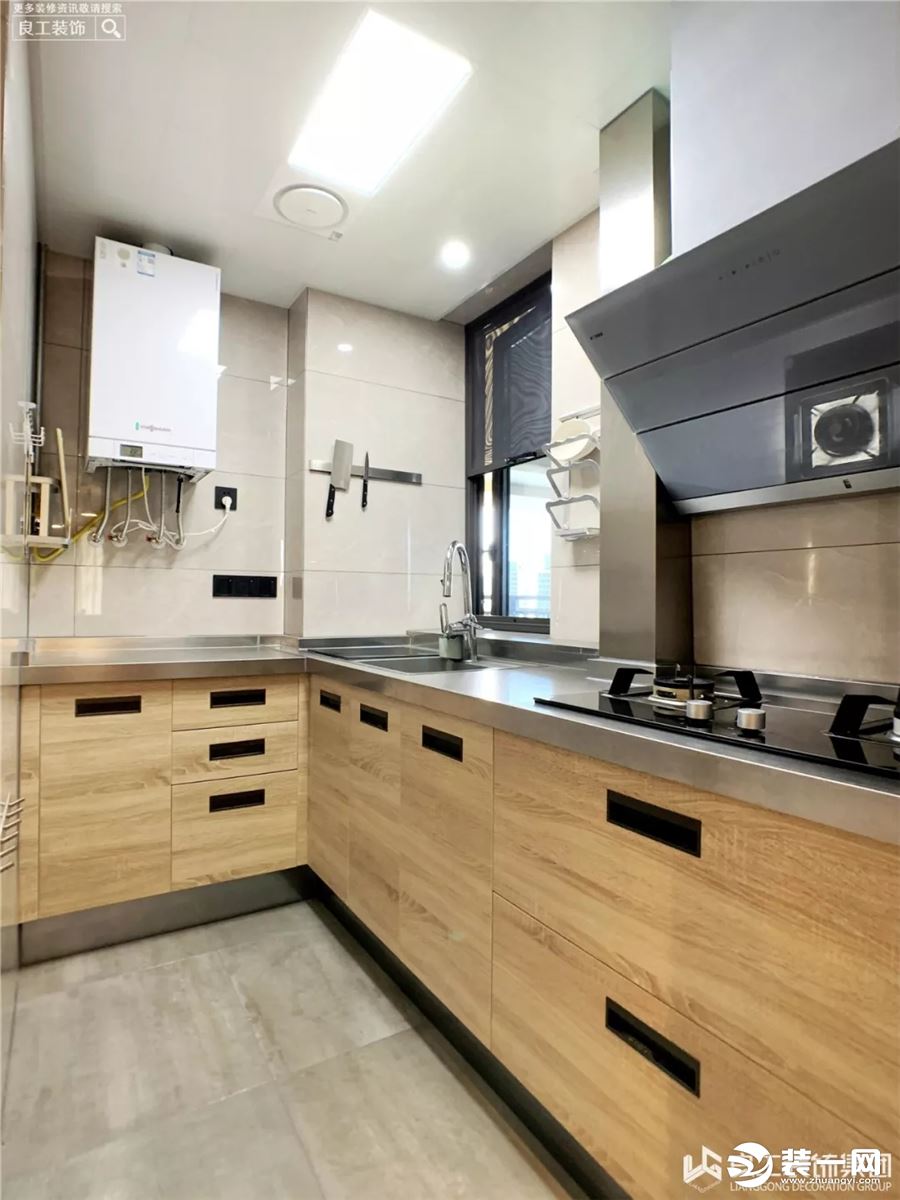 打开冰箱侧面的隐形门便是厨房，L型橱柜设计是小空间厨房的常用方法，简单黑白灰和原木搭配，自然时尚