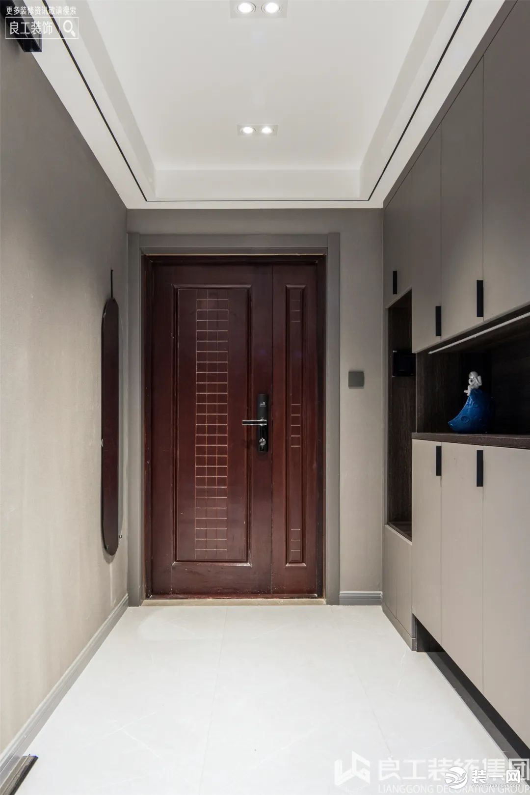 玄关左侧是一排顶天立地的玄关柜，利用柜子和地板色彩上的深浅对照，形成空间的层次感