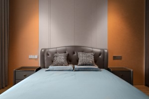  床头背景墙做了灰色硬包，嵌入线条，既有效拉伸空间层次感，也与爱马仕橙色的墙面，形成时髦的撞色效果。