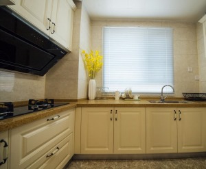 厨房采用L型的设计，增大了空间利用，橱具门板白色模压门扇仿木纹色看起来干净、利落。
