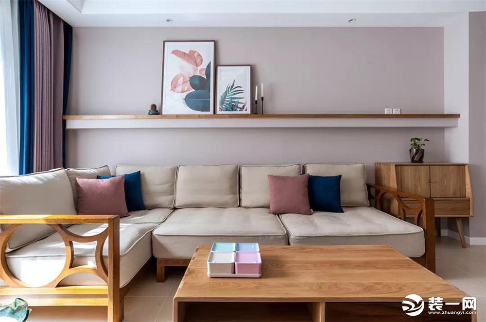 一套轻松舒适的布艺沙发，沙发墙上装一块长条搁板，并在上边摆上装饰画，整体显得格外的清新精致。