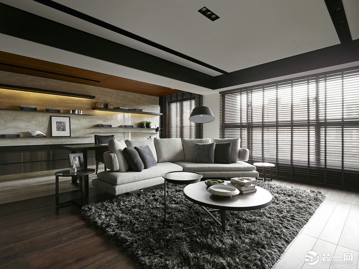 客厅灰色拐角沙发摆放在空间的中心，毛绒地毯的铺垫，与大小不一的圆桌设计，简单有格调。