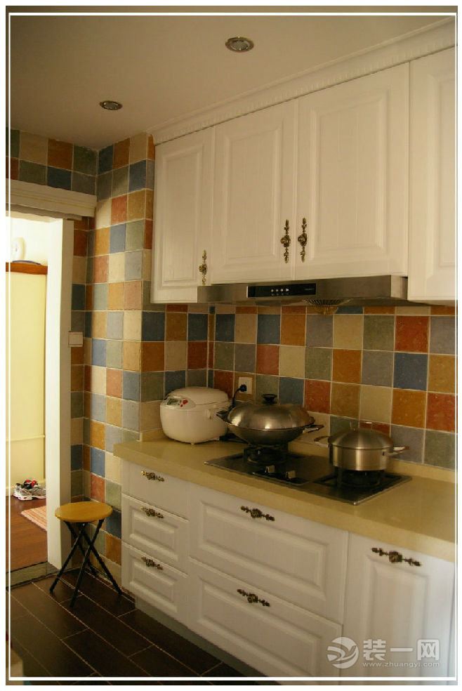 厨房的瓷砖颜色各异，组合起来色彩鲜明，白色橱柜显得十分精致，为业主提供了高效的下厨环境。