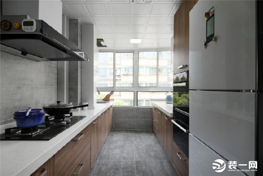 厨房通畅明亮，地面和墙壁采用灰色砖，增加了和谐感，搭配木质橱柜，给人干净整洁的即视感。