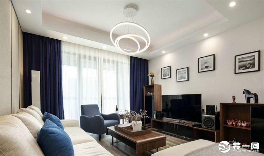 【客厅】房间整体以白色为主色调，进行了恰当的软装，将蓝色融入到设计中，搭配木质家具，圆圈环绕的灯管在